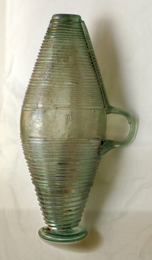 Glasgefäß in Form eines Fasses: Dies ist eine hohe Glasblaskunst. Die Glasmasse war hellgrün und die glasfarbenen Fäden sowie der Henkel sind aufgeschmolzen. Die Glaswand ist erstaunlich dünn.